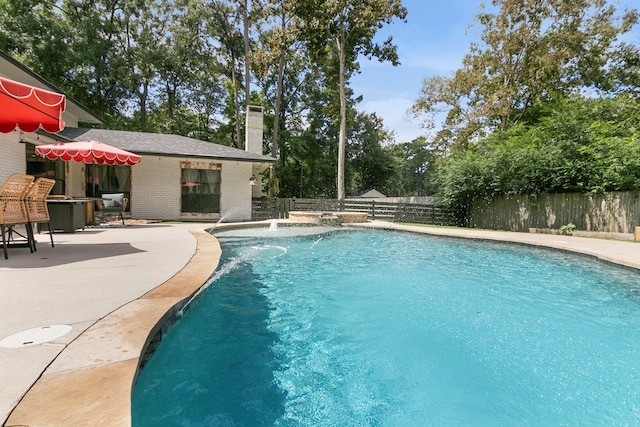 view of swimming pool with pool water feature and a patio