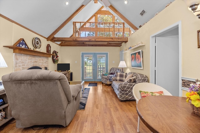 living room featuring french doors, light wood-type flooring, ceiling fan, high vaulted ceiling, and a stone fireplace