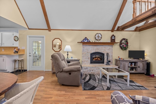 living room featuring a fireplace, vaulted ceiling with beams, and light hardwood / wood-style floors