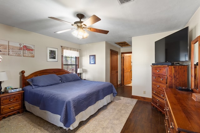 bedroom with a ceiling fan, visible vents, wood finished floors, and baseboards