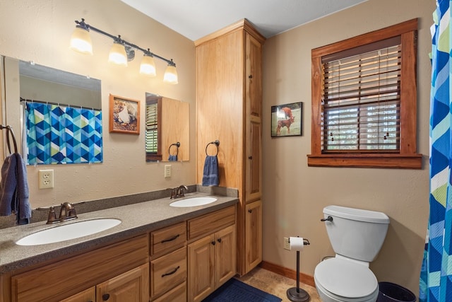 full bath with double vanity, toilet, baseboards, and a sink