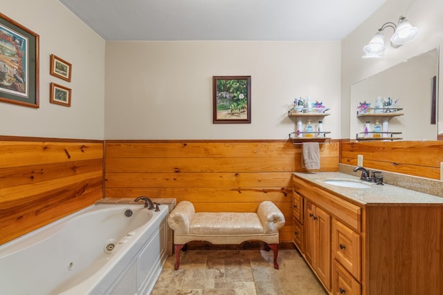 bathroom featuring a wainscoted wall, a tub with jets, wood walls, and vanity