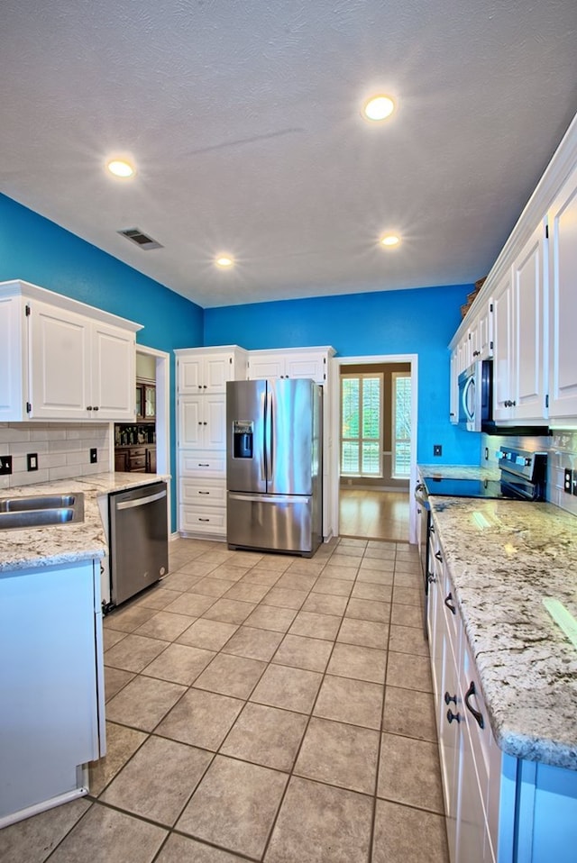 160 Somerset, Milam, TX 75959 - kitchen with white cabinets, appliances with stainless steel finishes, decorative backsplash, and light tile patterned flooring