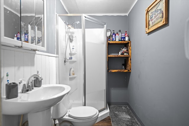 bathroom featuring a stall shower, crown molding, toilet, a sink, and wood finished floors