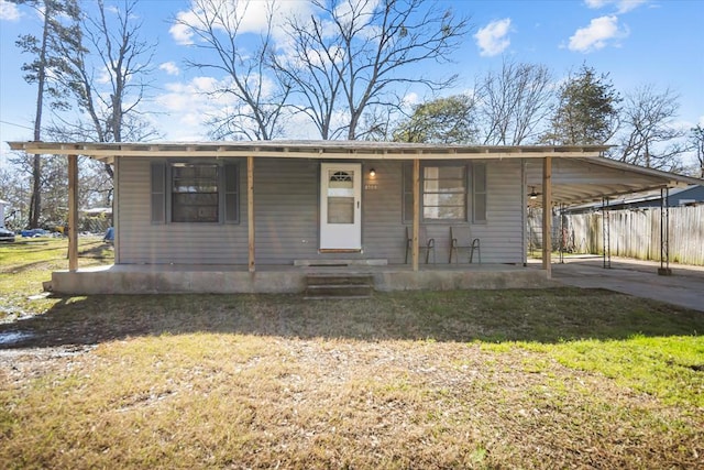 view of front of house with driveway, an attached carport, a front yard, a porch, and fence