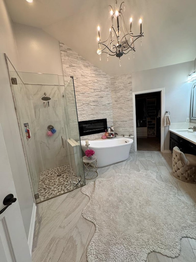 bathroom featuring lofted ceiling, marble finish floor, vanity, a shower stall, and a freestanding bath