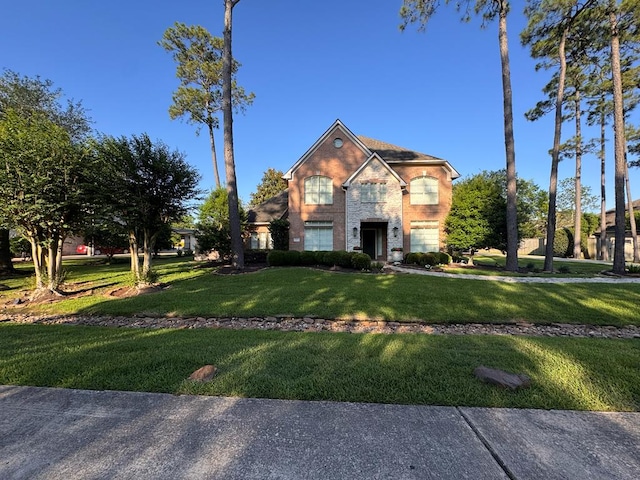 traditional-style home featuring a front yard, brick siding, an attached garage, and driveway