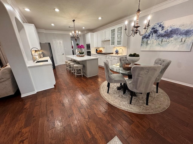 dining space featuring recessed lighting, baseboards, dark wood finished floors, a chandelier, and crown molding