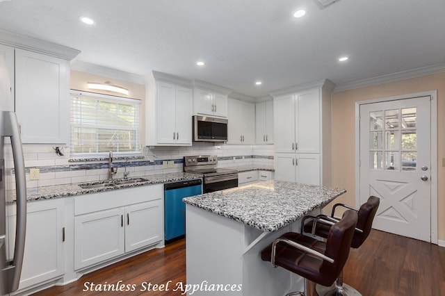309 Hunters Creek Dr, Lufkin, TX 75901 - kitchen with appliances with stainless steel finishes, crown molding, white cabinetry, backsplash, and a kitchen island