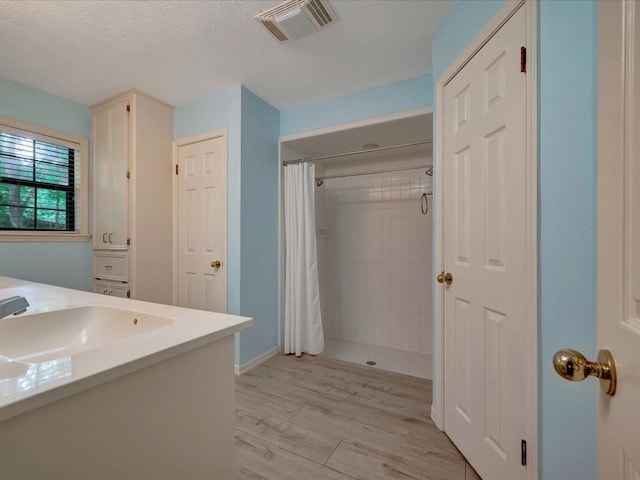 bathroom with a shower with curtain, wood-type flooring, a textured ceiling, and vanity