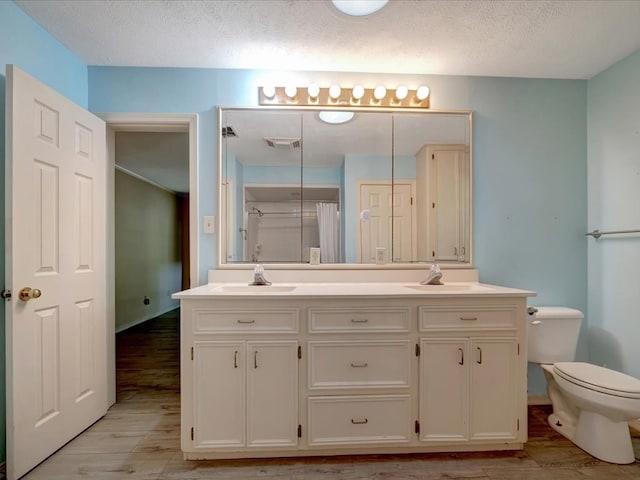 bathroom with toilet, vanity, a textured ceiling, and hardwood / wood-style flooring