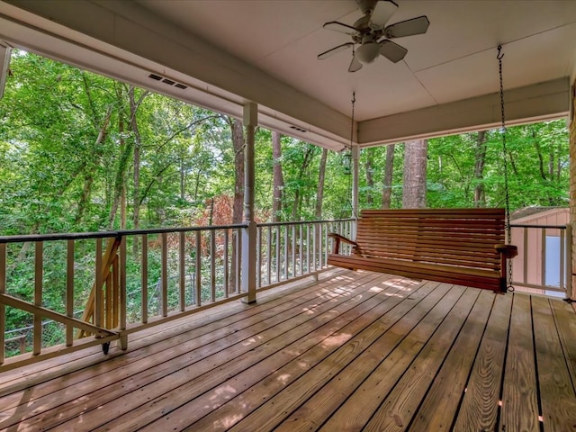 wooden deck with ceiling fan and a storage unit