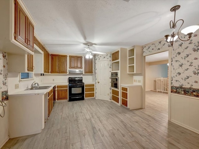 kitchen featuring gas stove, light hardwood / wood-style flooring, stainless steel oven, and decorative light fixtures