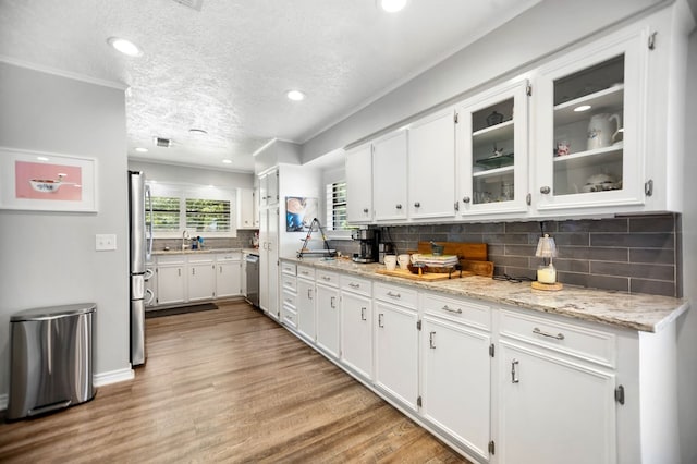 1405 Oak Hill Pl, Lufkin, TX 75904 - kitchen featuring appliances with stainless steel finishes, white cabinets, light wood-style flooring, backsplash, and recessed lighting