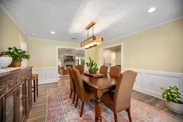 1405 Oak Hill Pl, Lufkin, TX 75904 - dining space featuring a fireplace, a decorative wall, a wainscoted wall, a textured ceiling, and ceiling fan