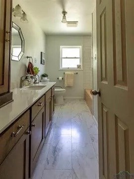bathroom featuring toilet, marble finish floor, shower / tub combination, and vanity
