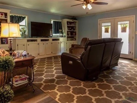 living area with ornamental molding, a ceiling fan, and french doors