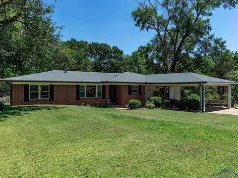 ranch-style house with brick siding, concrete driveway, a front lawn, and an attached carport