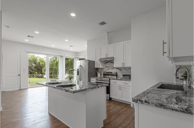 20 Coolcrest Dr, Point Blank, TX 77364 - kitchen featuring appliances with stainless steel finishes, under cabinet range hood, tasteful backsplash, wood finished floors, and light stone counters