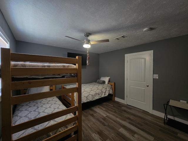 bedroom with a textured ceiling, ceiling fan, and dark wood-type flooring