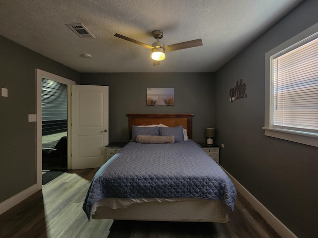 bedroom featuring ceiling fan, wood-type flooring, and a textured ceiling