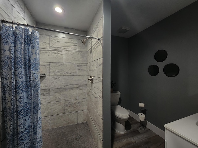 bathroom with hardwood / wood-style floors, vanity, toilet, and curtained shower