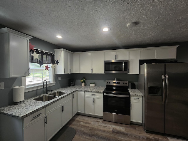 kitchen with white cabinets, sink, a textured ceiling, dark hardwood / wood-style flooring, and stainless steel appliances