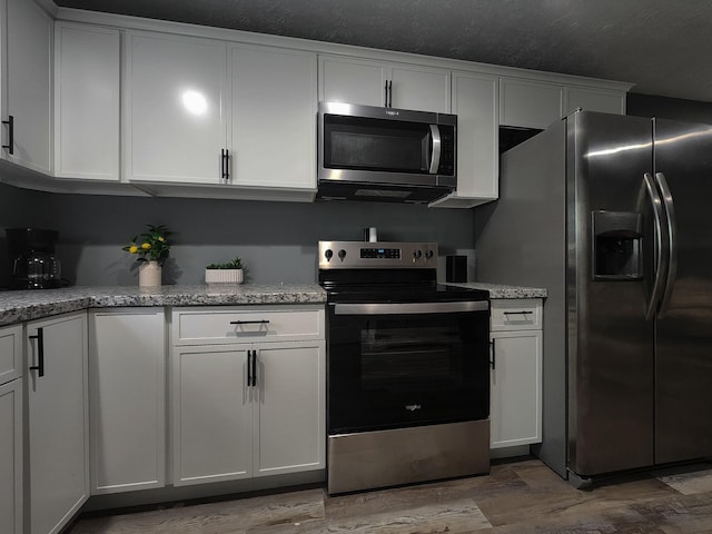 kitchen featuring white cabinetry, light stone countertops, and appliances with stainless steel finishes