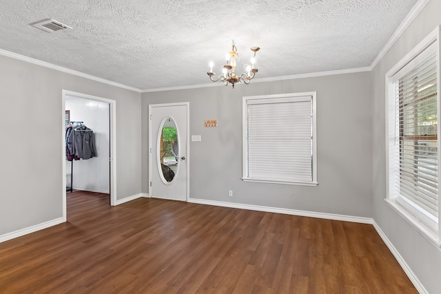 entrance foyer featuring dark hardwood / wood-style flooring, a chandelier, a textured ceiling, and ornamental molding