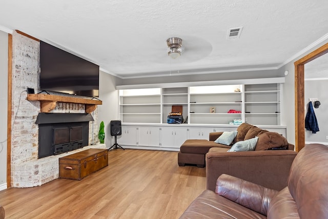 living room featuring a textured ceiling, light wood-type flooring, ceiling fan, and ornamental molding