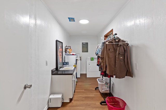 hallway with washer and clothes dryer, electric panel, sink, light wood-type flooring, and ornamental molding