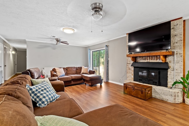 living room with a fireplace, a textured ceiling, light hardwood / wood-style floors, and ornamental molding