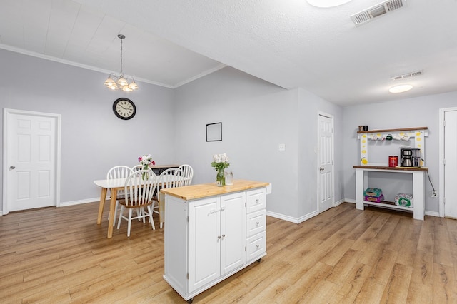 240 W 7th St, Trinity, TX 75862 - kitchen with white cabinetry, light wood-type flooring, crown molding, butcher block counters, and baseboards
