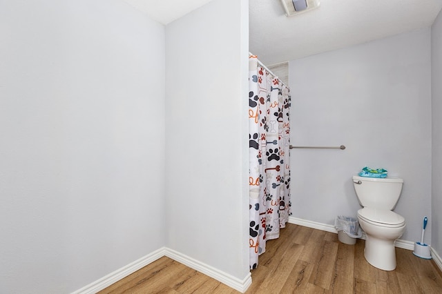 240 W 7th St, Trinity, TX 75862 - bathroom featuring wood finished floors, baseboards, toilet, and a shower with curtain