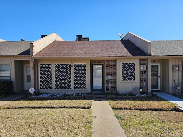 view of front of house featuring a front yard, board and batten siding, and roof with shingles