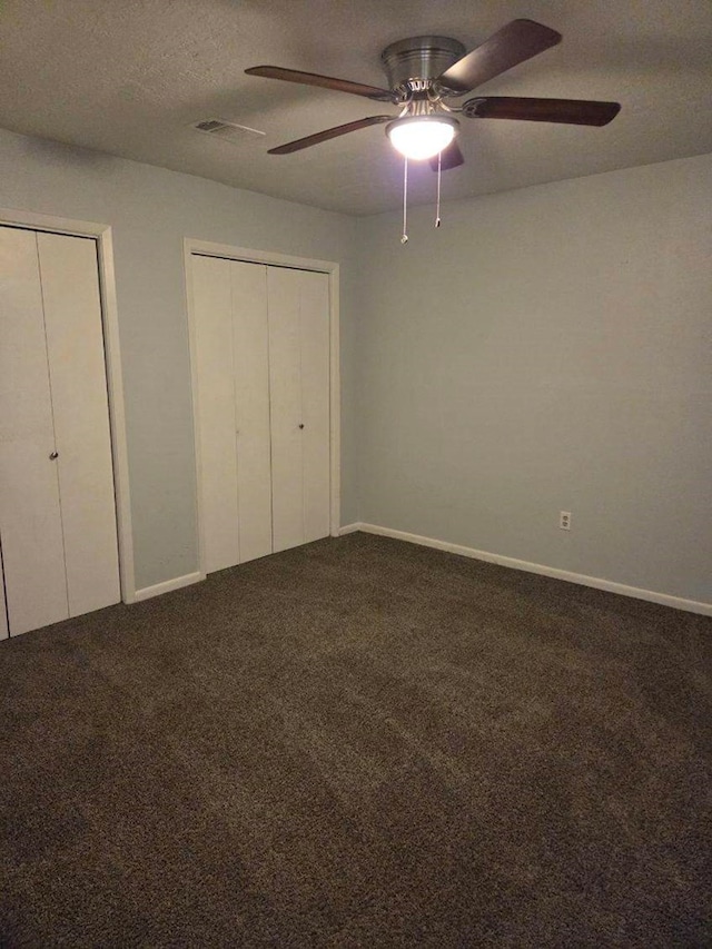 unfurnished bedroom with visible vents, multiple closets, a textured ceiling, carpet flooring, and baseboards