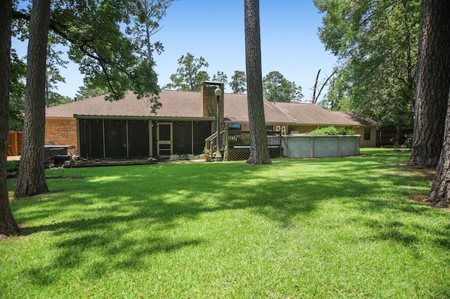 4 Pinemont Pl, Lufkin, TX 75904 - rear view of house featuring a sunroom, a yard, an outdoor pool, a chimney, and roof with shingles