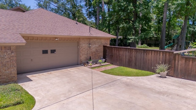 4 Pinemont Pl, Lufkin, TX 75904 - view of side of property featuring brick siding, driveway, roof with shingles, a garage, and a playground