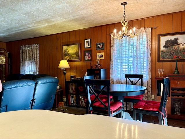 dining room featuring wooden walls and an inviting chandelier