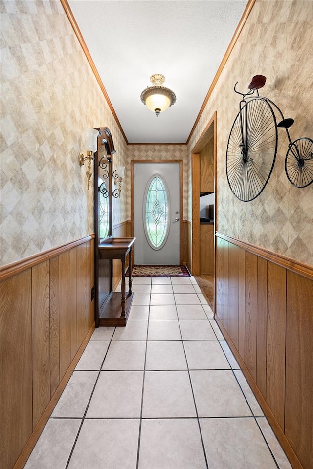 doorway to outside with wood walls, ornamental molding, and light tile patterned floors