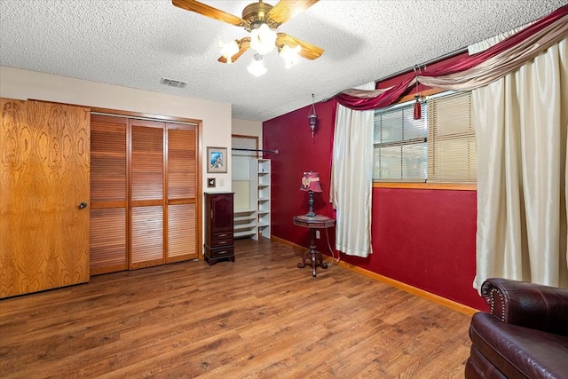 interior space featuring ceiling fan, a textured ceiling, and hardwood / wood-style flooring