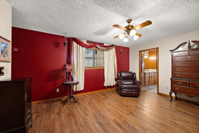 living area with a textured ceiling, hardwood / wood-style flooring, and ceiling fan