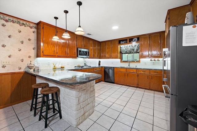 kitchen featuring kitchen peninsula, sink, light tile patterned floors, and appliances with stainless steel finishes