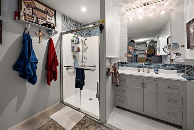 bathroom with tasteful backsplash, vanity, a shower with shower door, and hardwood / wood-style flooring