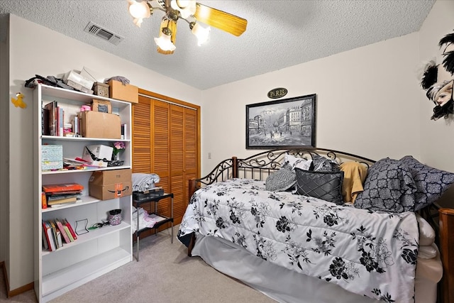 bedroom with carpet flooring, ceiling fan, a closet, and a textured ceiling