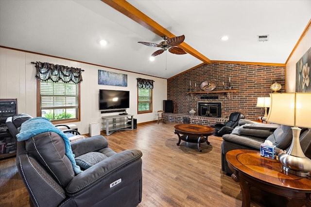 living room featuring a wood stove, vaulted ceiling with beams, ceiling fan, wood-type flooring, and brick wall