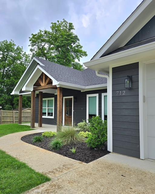 doorway to property with fence and roof with shingles