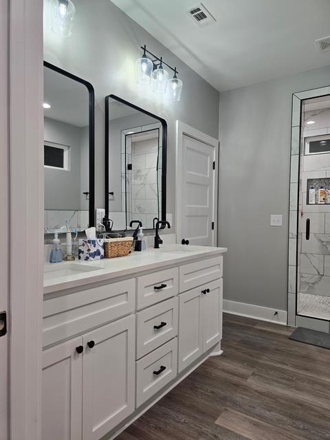 full bathroom with wood finished floors, visible vents, a sink, and a stall shower