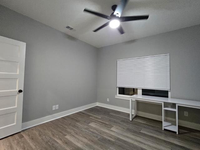 unfurnished office featuring baseboards, ceiling fan, visible vents, and wood finished floors