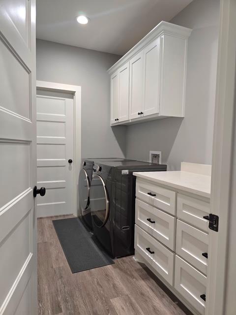 clothes washing area featuring cabinet space, recessed lighting, light wood-style flooring, and washer and dryer